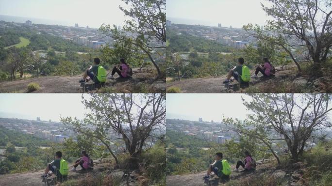 背包客的孩子坐在山顶上，一起看着风景，夏天的生活方式和冒险概念。
