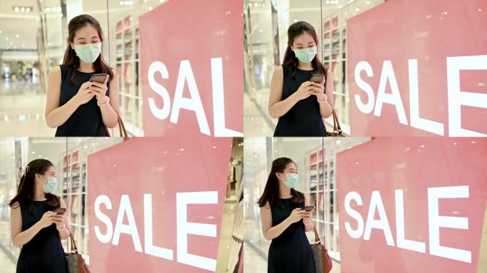 Asain妇女在现代购物中心商店的销售广告牌上停下来，并在降价和促销时去购物。
