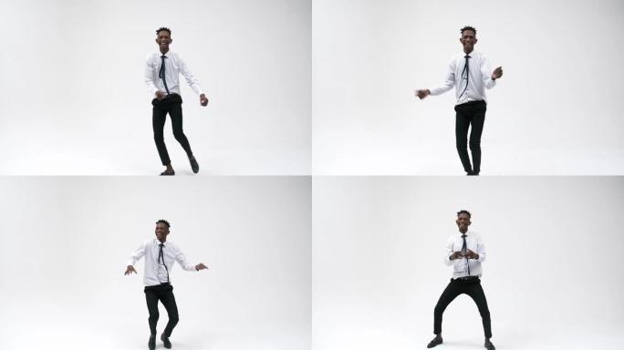 穿着西装的黑人办公室男子在白色背景下在演播室里富有表现力地跳舞，微笑着。黑人上班族起跳。成功和快乐的
