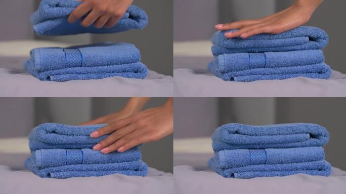 面目全非的女人的手把干净的浴巾放在床上。客房服务。家庭日常生活。背景模糊