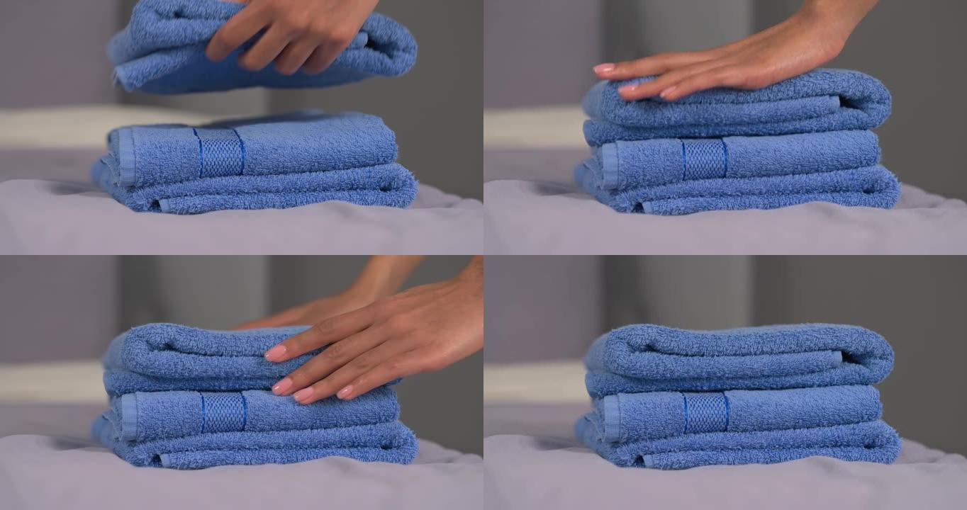 面目全非的女人的手把干净的浴巾放在床上。客房服务。家庭日常生活。背景模糊