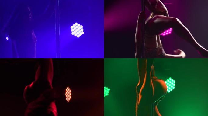 舞蹈演员在一个黑暗的演播室里倒立着绕着钢管旋转。一个苗条的运动员身体的剪影在黑色的背景与彩色的光。有