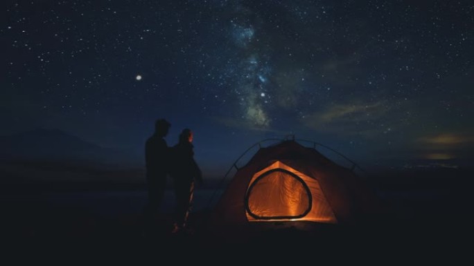 这对年轻夫妇在星空背景下的营地中休息