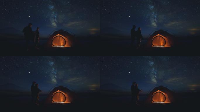 这对年轻夫妇在星空背景下的营地中休息
