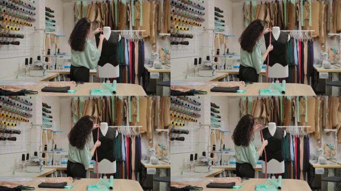 女裁缝正在用卷尺测量裁缝假人的衣服。女人专注而体贴。工作室轻巧，现代，有许多缝纫工具和物品。