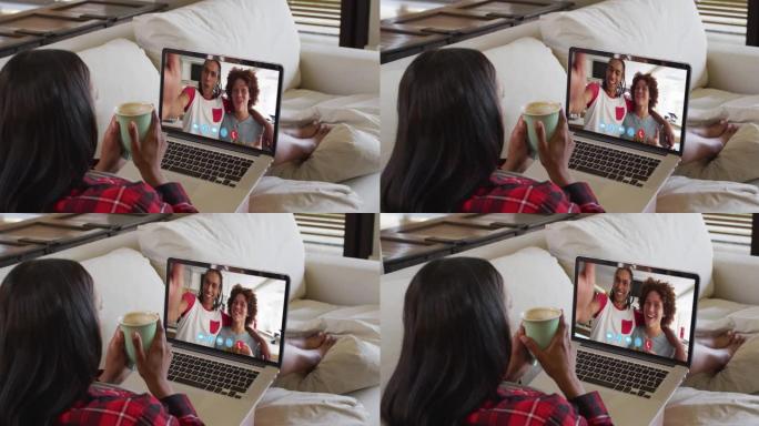 混血女人坐在沙发上，用笔记本电脑与朋友进行视频通话