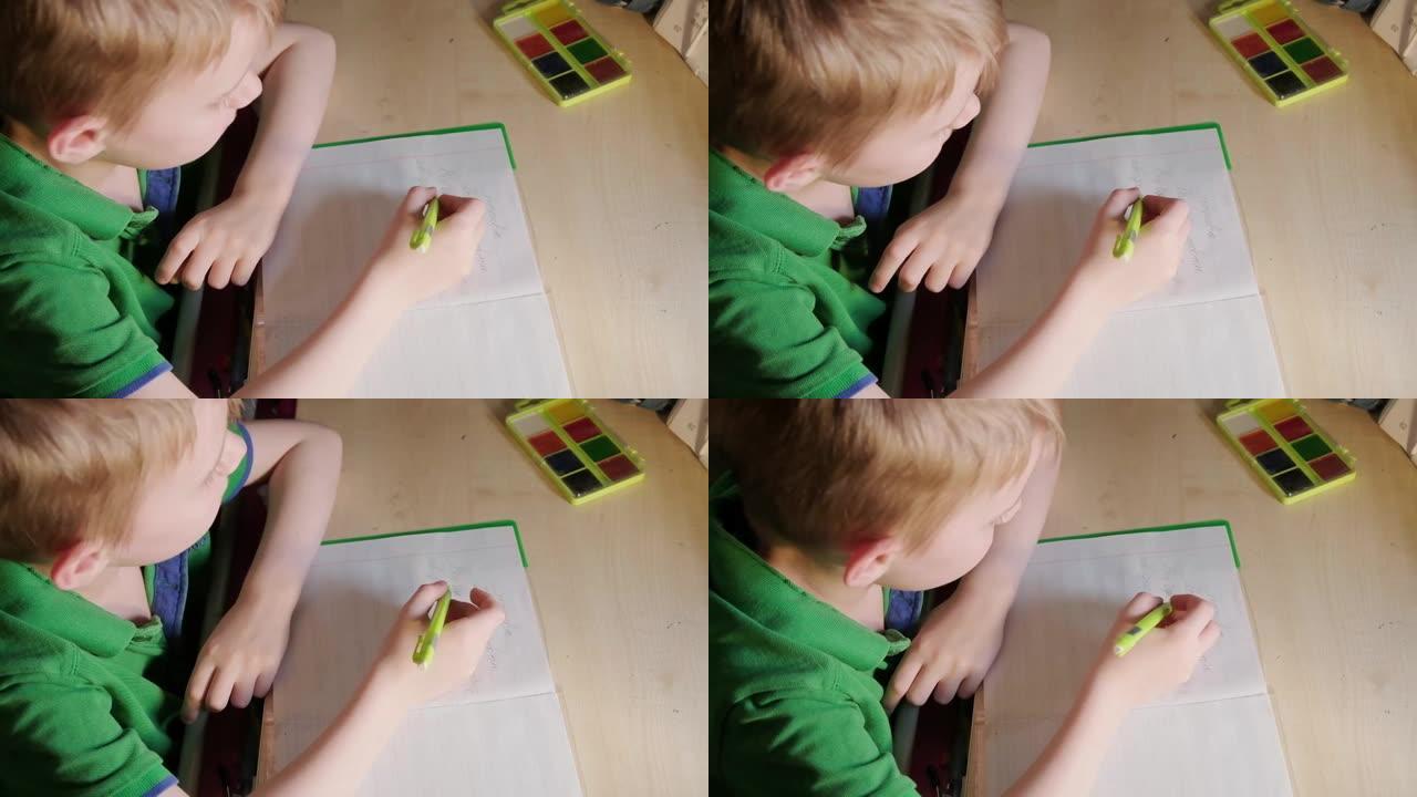 一个小男孩正在桌边做作业。在笔记本上写学校的作业。