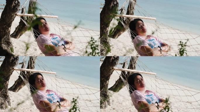 暑假在海滩的吊床上休息和睡觉的亚洲妇女