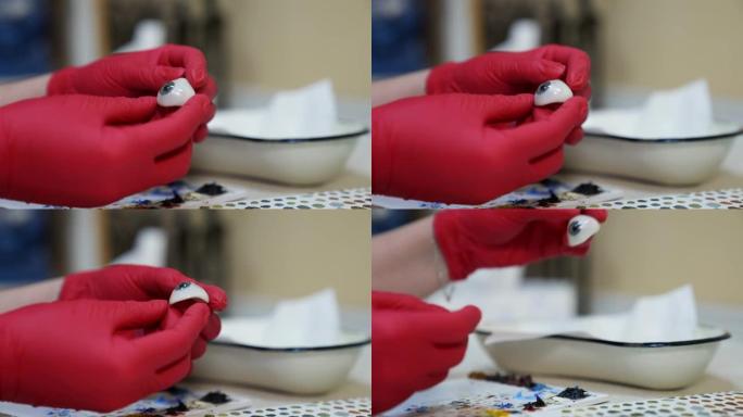 Ophtalmologist手握塑料眼球。眼睛的详细模型。选择性专注于红色乳胶手套的手。
