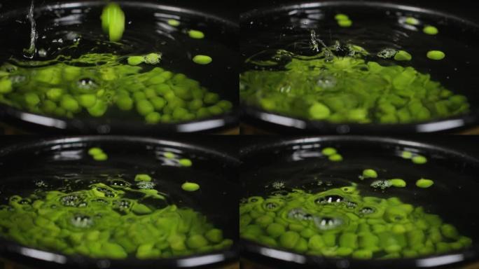 慢动作关闭下降的绿豌豆背景。宏观拍摄新鲜有机豌豆掉落。蔬菜收获健康饮食。美丽的纹理特写新鲜的绿豌豆。