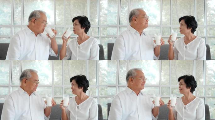 肖像亚洲老年夫妇在家沙发上喝牛奶