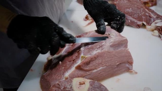 屠夫用刀割肉。切掉肉块。肉制品的生产。特写