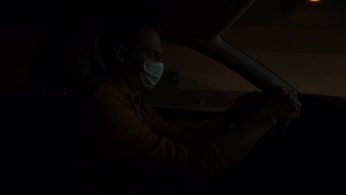 蒙面人开车驶出黑暗的隧道进入光明。他握着方向盘的手。