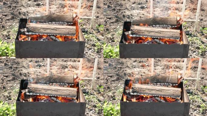火盆特写，柴火燃烧着明亮的火焰。白天烧柴木炭烧烤。篝火特写镜头起火。选择性聚焦，浅景深。