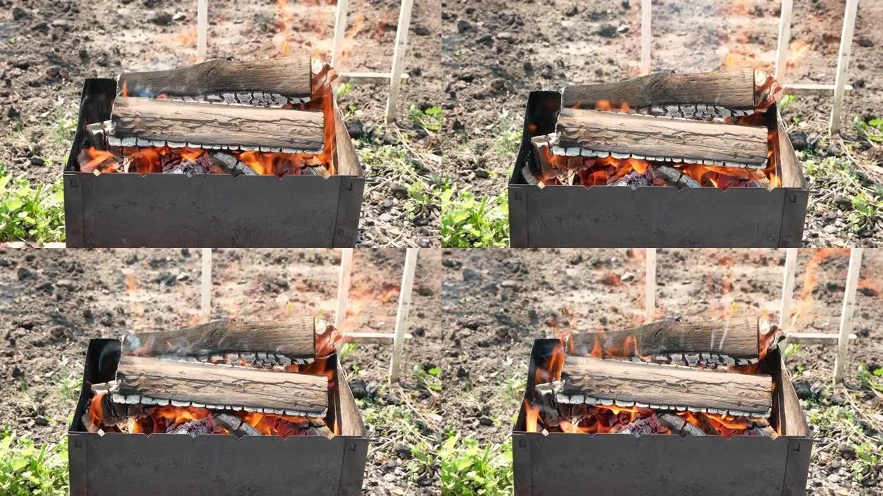 火盆特写，柴火燃烧着明亮的火焰。白天烧柴木炭烧烤。篝火特写镜头起火。选择性聚焦，浅景深。