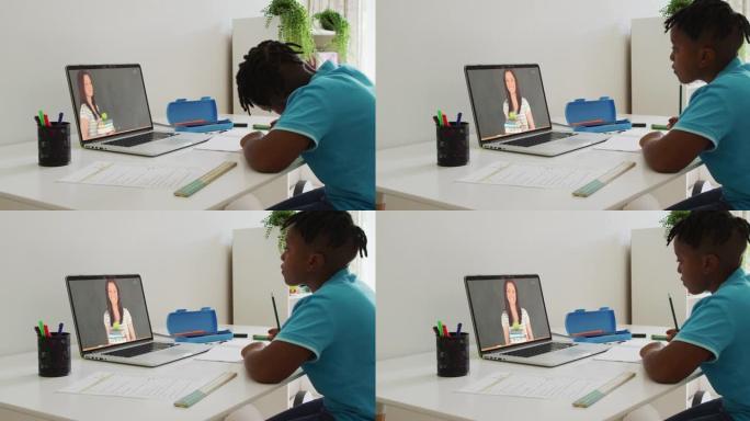 非裔美国男孩在家里用笔记本电脑与女老师进行视频通话时做作业