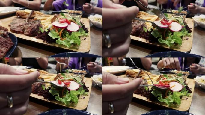 女人用叉子在餐厅的木托盘里拿沙拉蔬菜吃