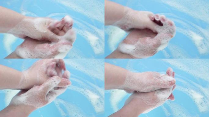 一名妇女在带有泡沫的蓝色背景上撒上泡沫，特写镜头。女人的手在肥皂泡沫。如何正确洗手。视频剪辑高清
