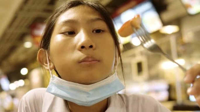 亚洲女学生穿着制服，和哥哥一起在美食广场吃香肠，生活方式理念。