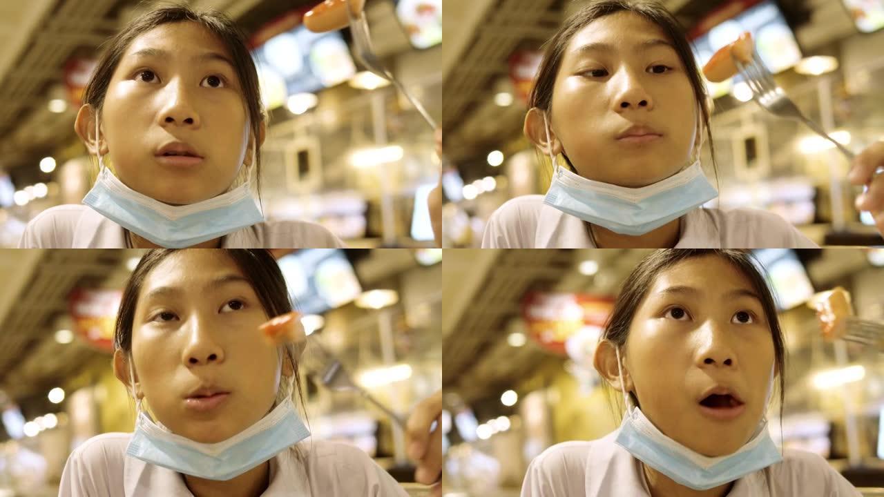 亚洲女学生穿着制服，和哥哥一起在美食广场吃香肠，生活方式理念。