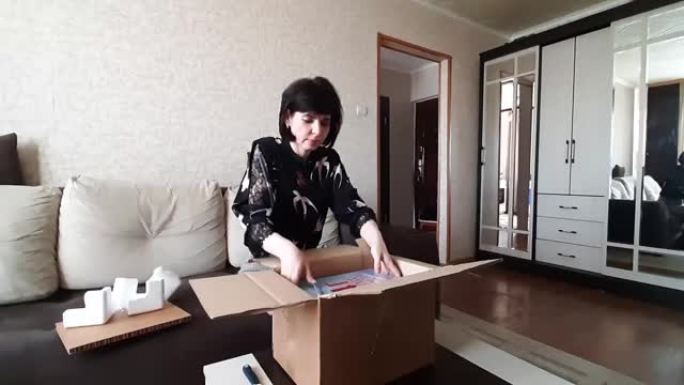 女人坐在家里的沙发上打开一个装有货物的包裹