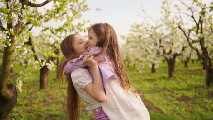 两个女孩姐妹玩得开心，在花园里用开花的树拥抱。