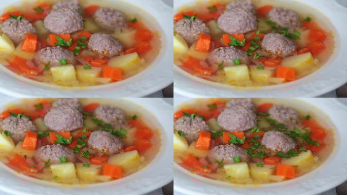 肉丸汤，土豆，胡萝卜和欧芹放在白盘中。舒适食品概念。