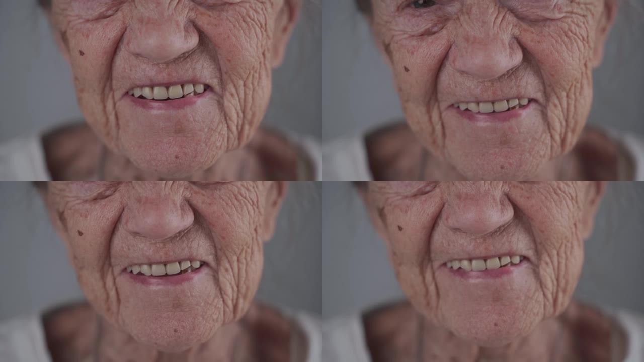 微笑的老年高级女士，在灰色背景的工作室里用假牙做假牙。积极和长寿。养老金领取者感到满意。你永远不会老