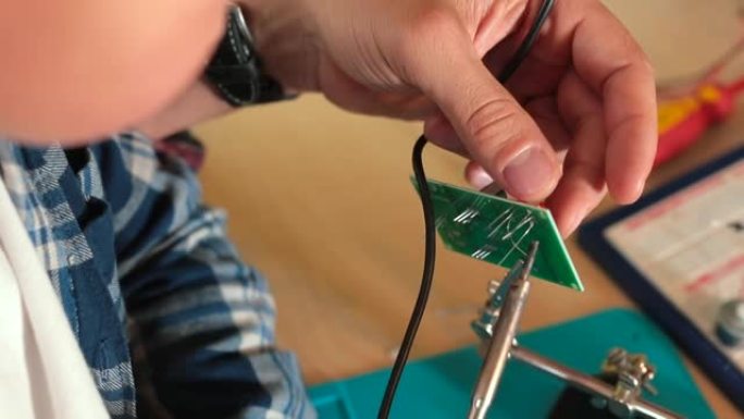 精细运动技能老师的手在电子板上焊接细节。