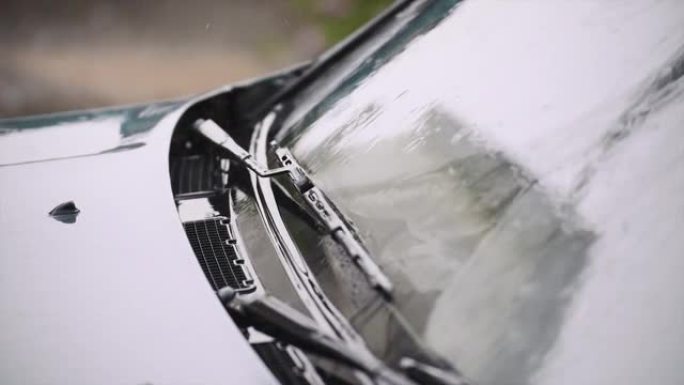 雨水落在外面黑色汽车的挡风玻璃和引擎盖上。