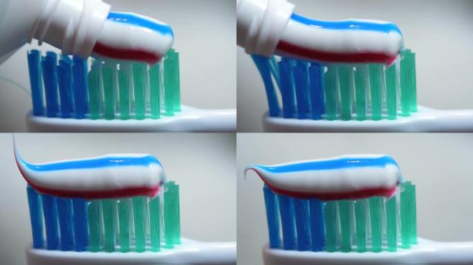 带有明亮条纹牙膏的特写牙刷。宏观拍摄红色和蓝色条纹牙膏挤到牙刷特写上。牙齿保健或口腔卫生。早上刷牙。