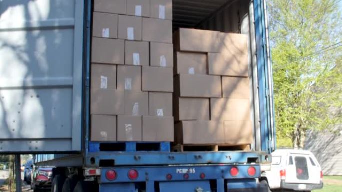 在一辆半卡车的后面，成堆的盒装食物捐赠