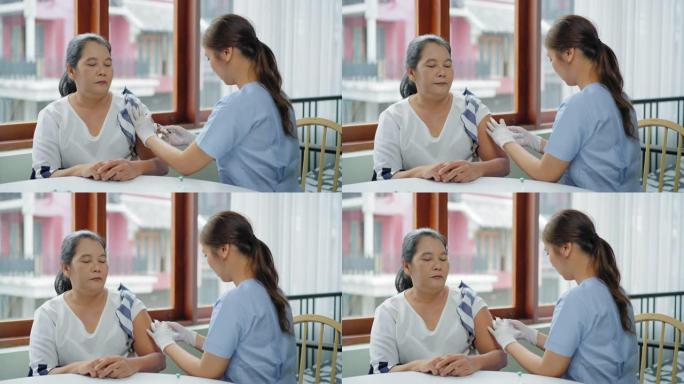 这位亚洲高级妇女害怕针头，在家里接受疫苗，看到护士用医用注射器注射疫苗。一位老人在家中处于检疫状态，