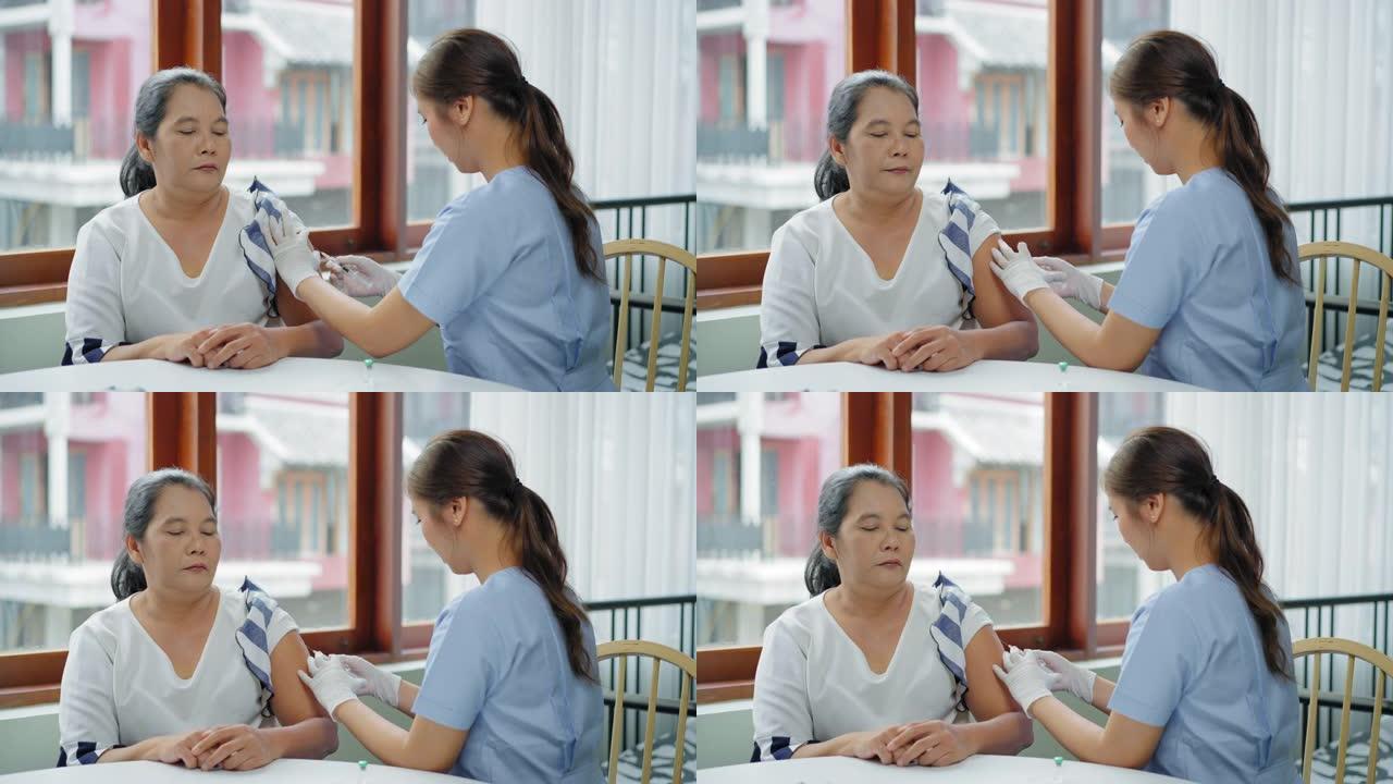 这位亚洲高级妇女害怕针头，在家里接受疫苗，看到护士用医用注射器注射疫苗。一位老人在家中处于检疫状态，