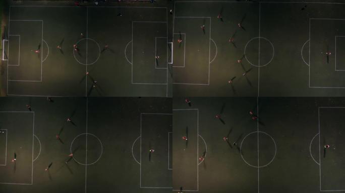 无人机在足球场射击，青少年在夜间体育场踢足球。小男孩在夜间体育场鸟瞰图与教练踢足球。