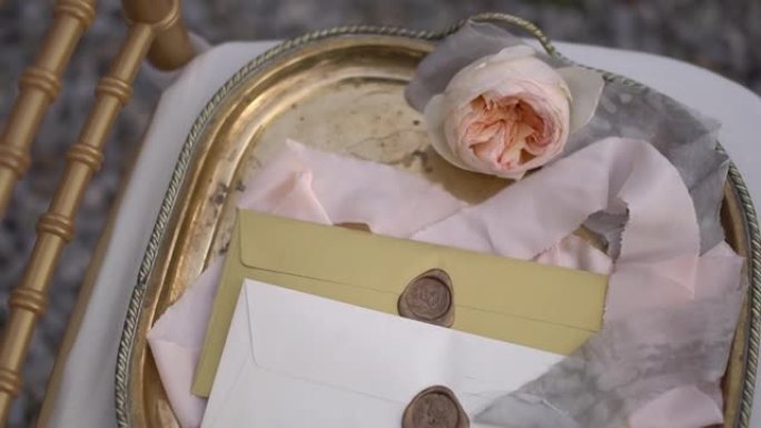 精美的复古托盘上有蜡封、精致的奶油玫瑰和丝带的信封