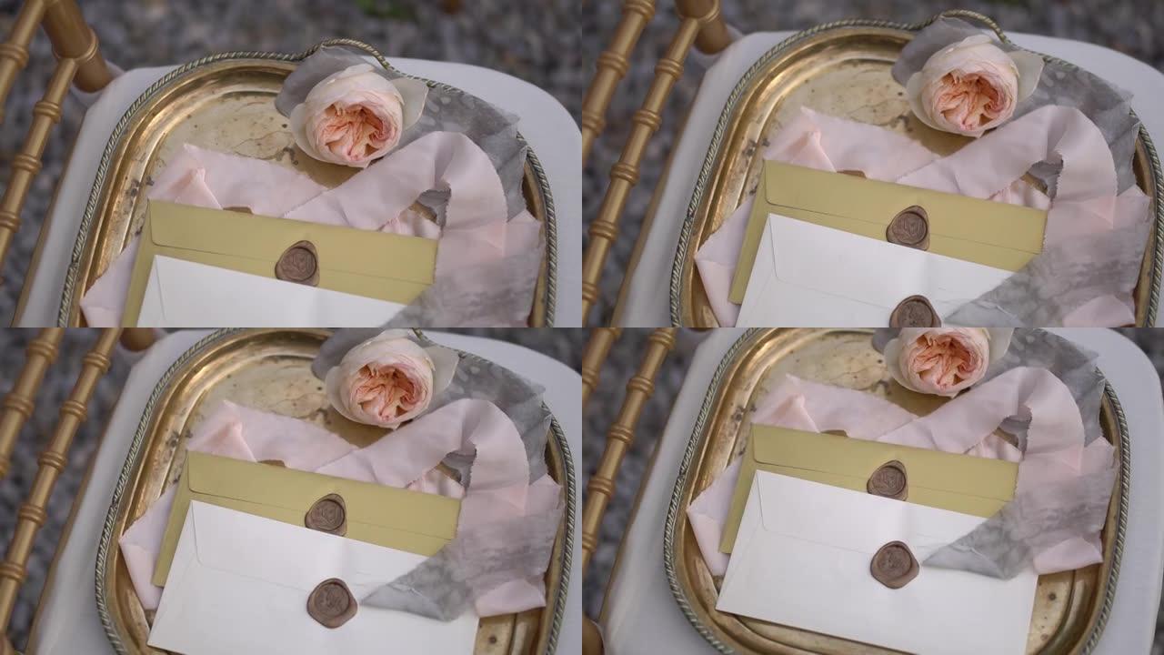 精美的复古托盘上有蜡封、精致的奶油玫瑰和丝带的信封