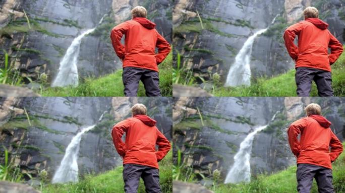 游客站在森林里，靠近突然的石墙，看着美丽的瀑布