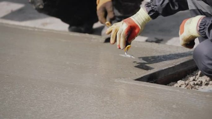 匿名混凝土工人平整潮湿的人行道。浇筑混凝土。一名工厂工人用铲子平整并平整地板上的湿混凝土