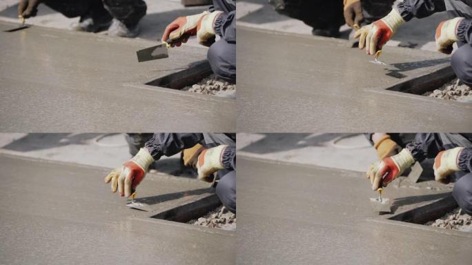 匿名混凝土工人平整潮湿的人行道。浇筑混凝土。一名工厂工人用铲子平整并平整地板上的湿混凝土