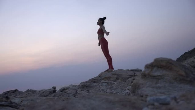 年轻女子站在山顶上瑜伽姿势。