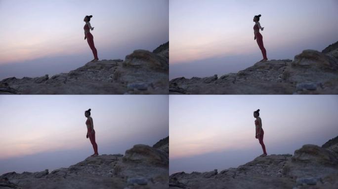年轻女子站在山顶上瑜伽姿势。