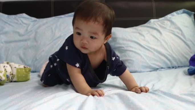 8个月的亚洲中国男婴肖像在床上惊奇地四处走动