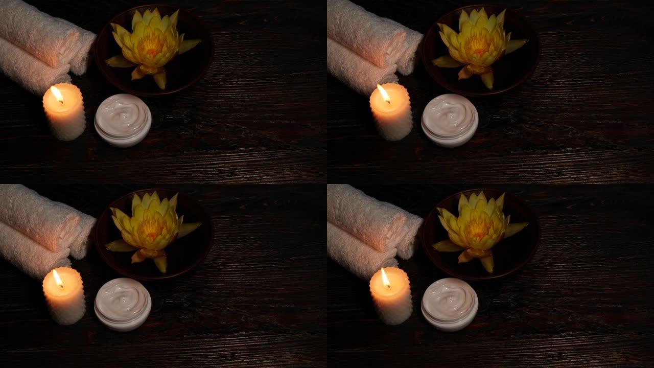 木桌上的莲花睡莲花、奶油、毛巾和蜡烛
