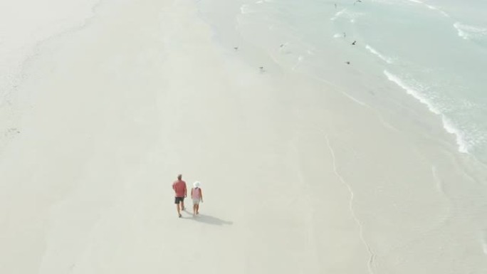 一对夫妇在海滩上放松漫步的4k无人机镜头