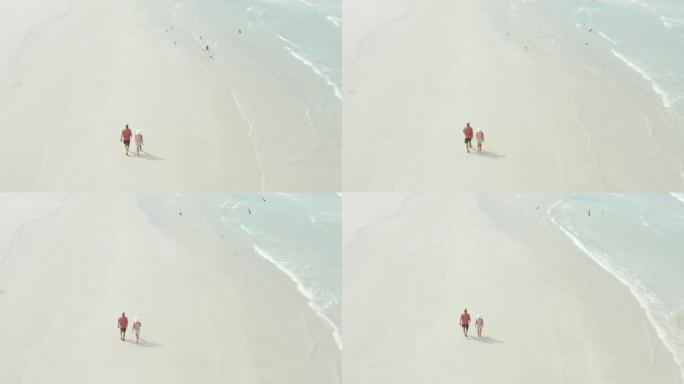 一对夫妇在海滩上放松漫步的4k无人机镜头