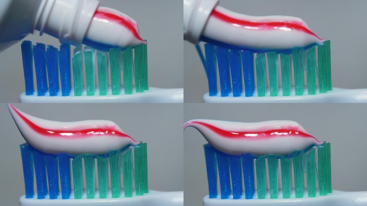 带有明亮条纹牙膏的特写牙刷。宏观拍摄红色和蓝色条纹牙膏挤到牙刷特写上。牙齿保健或口腔卫生。早上刷牙。
