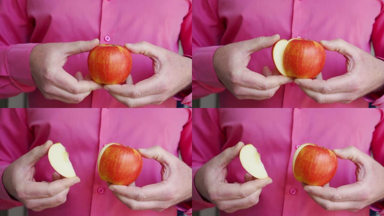 手持成熟多汁苹果的男性双手特写。分开苹果的一部分。