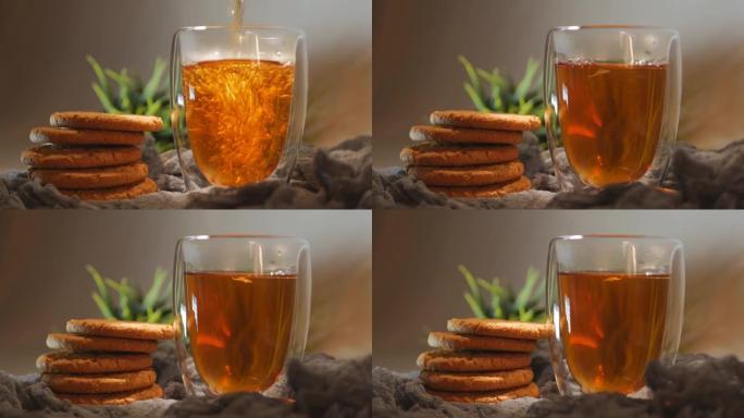 将热茶倒入双层玻璃杯中。将热茶倒入双层玻璃中。茶放在透明的玻璃杯里，饼干正在旋转。循环视频。特写。旋