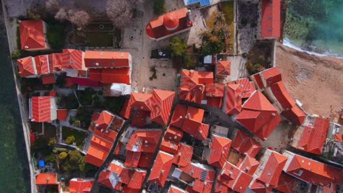 古老的布德瓦镇的历史悠久的红色屋顶建筑，黑山共和国的沙滩和蓝色波浪海在阳光空中全景